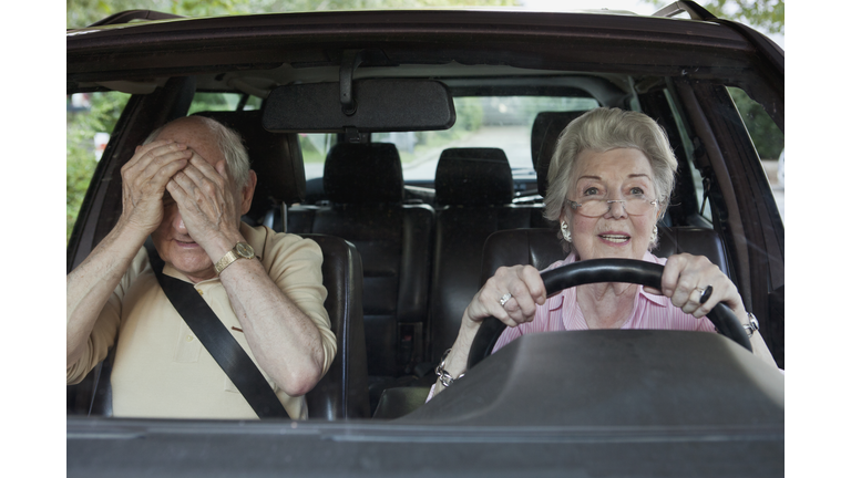 Woman has trouble driving while man in passenger seat despairs