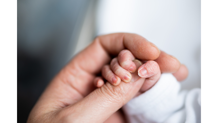 hand of newborn baby who has just been born holding the finger of his father's hand.