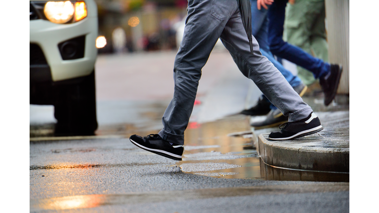 Man stepping over puddle in rain