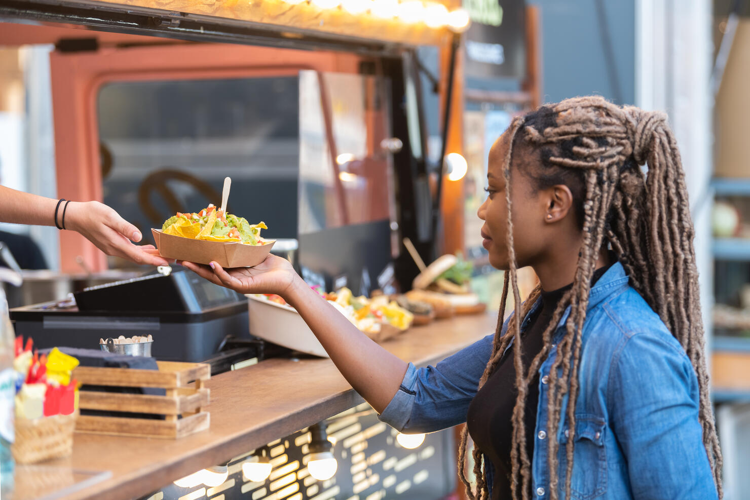 Satisfied afro american woman getting fast food tray with delicious nachos