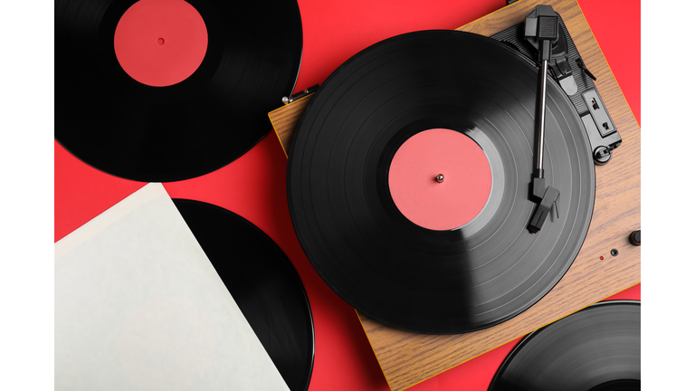 Modern player and vinyl records on red background, flat lay