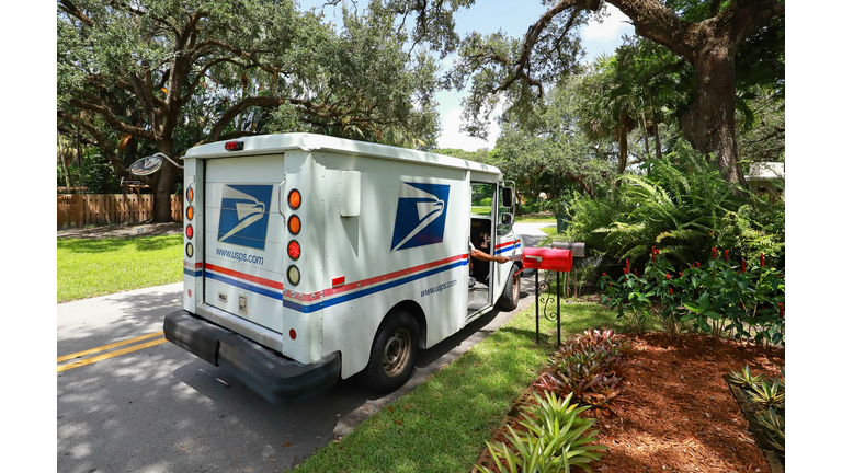 Mail carrier puts mail in a mail box