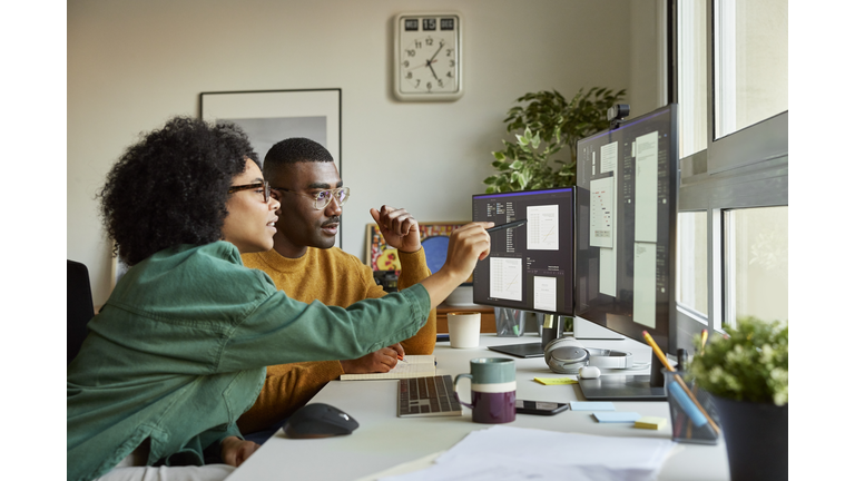 Multiracial colleagues discussing over computer