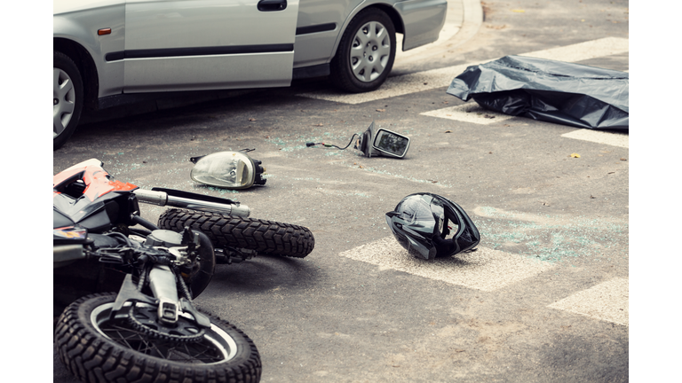 Black helmet and motorcycle on the road after fatal collision with a car