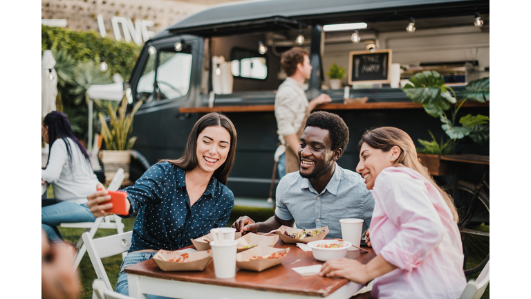 Multiracial people having fun doing selfie at food truck outdoor - Focus on african man face