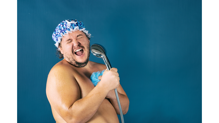 Funny fat man in blue cap sing in the shower