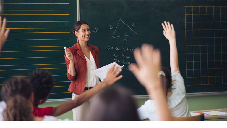 Teacher in front of her class, asking questions.