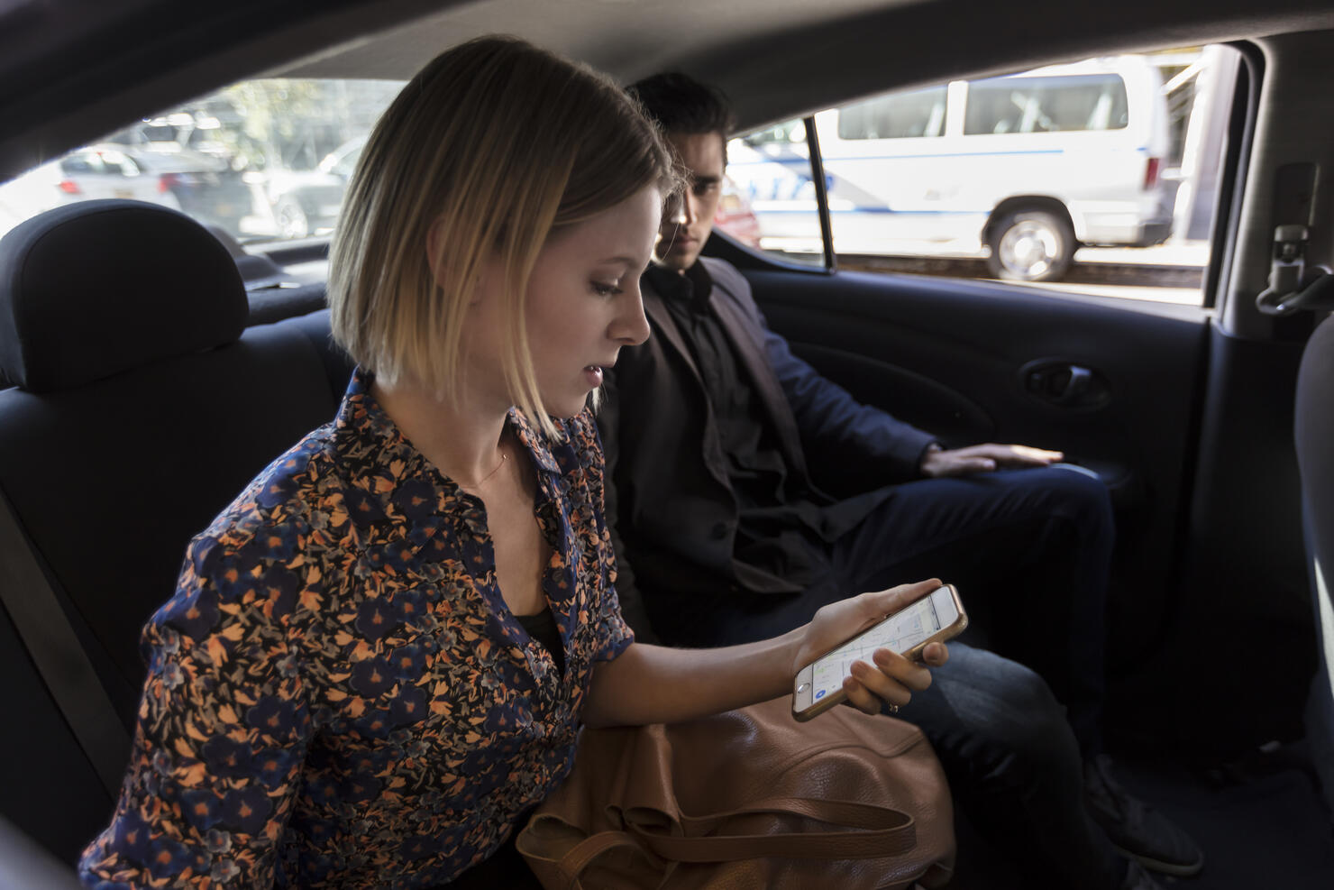 Man and woman sitting in car looking at phone