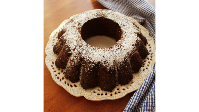 Chocolate bunt cake sprinkled with sugar powder on a plate white background