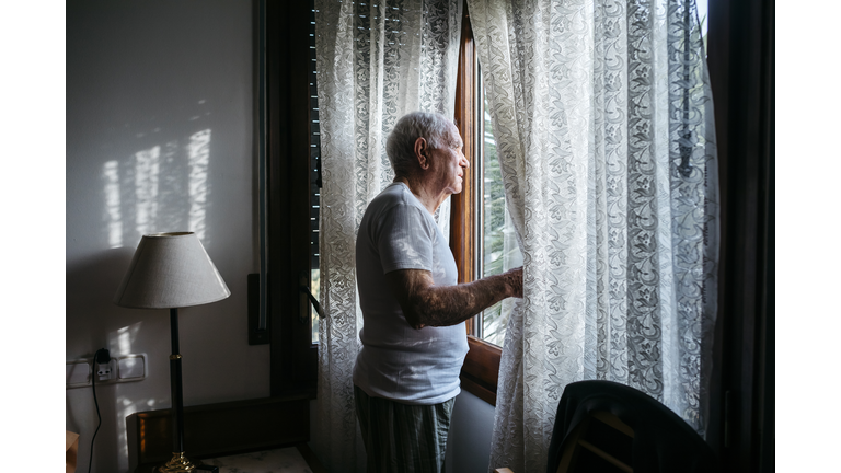 Man looking through window at home