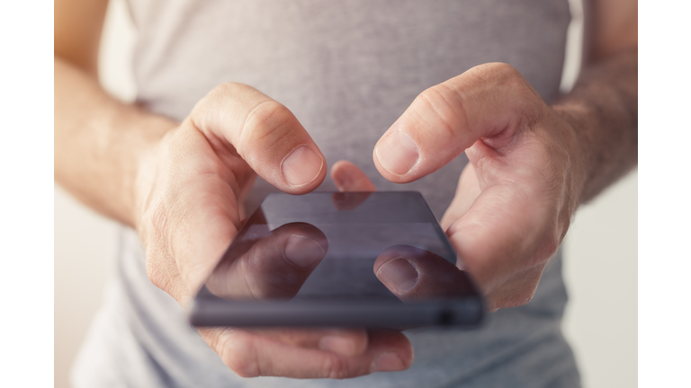 Close up of male hands typing text message on smartphone