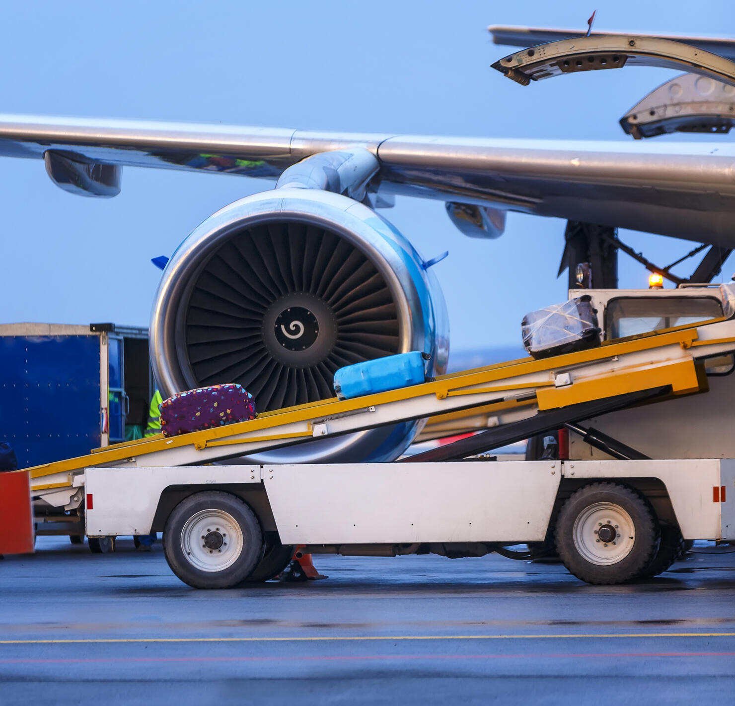 three suitcases are loaded on the transport ladder to the plane in airport