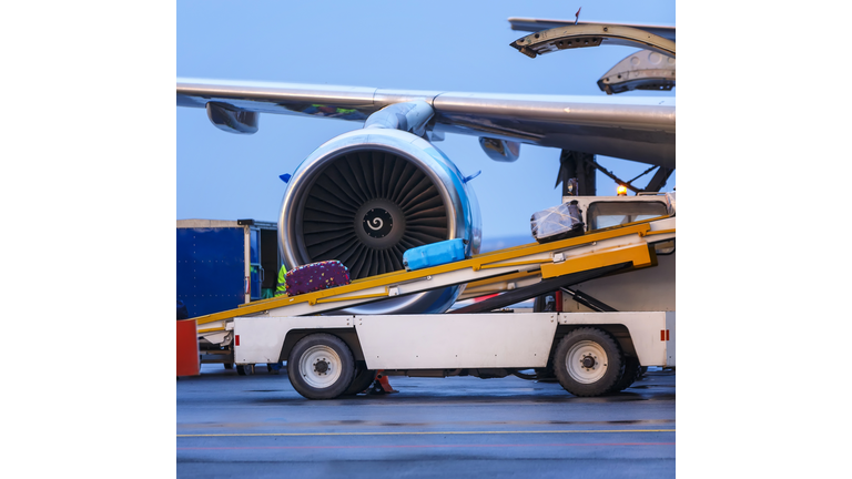 three suitcases are loaded on the transport ladder to the plane in airport