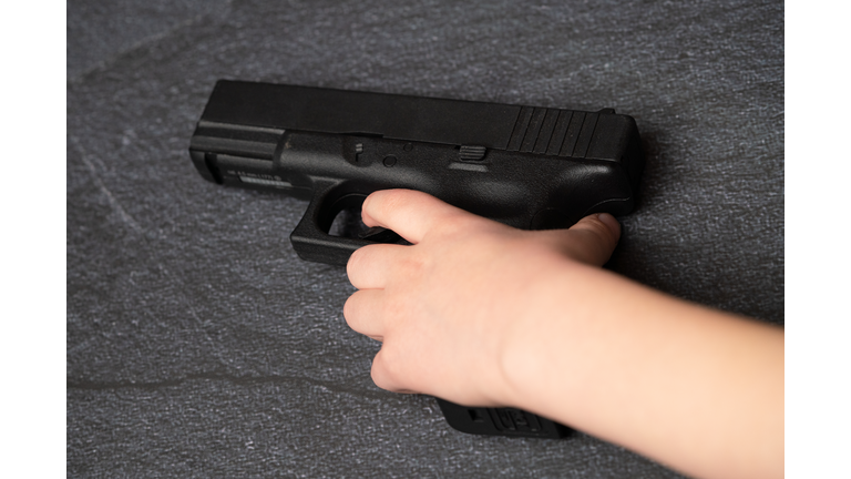 Young Caucasian White Child Kid Boy Hand Holding Black Gun Firearm Weapon