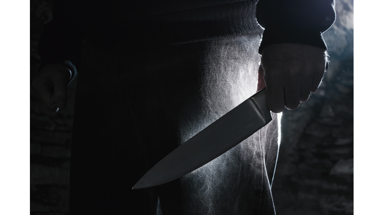 Dark photo of a man holding a big knife, crime concept.