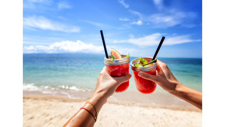 Fresh watermelon juice in two glasses against a bright tropical landscape, background of the sea.