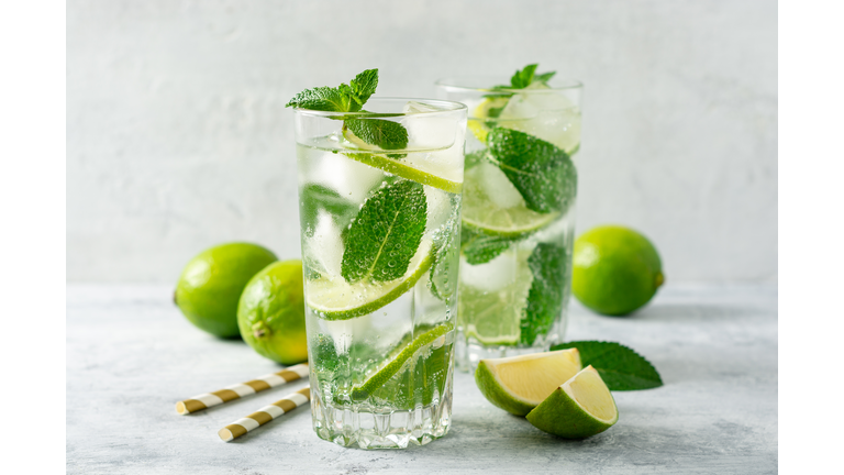 Fresh mojito cocktail with lime and mint in glass on concrete background. Cold refreshing drink.