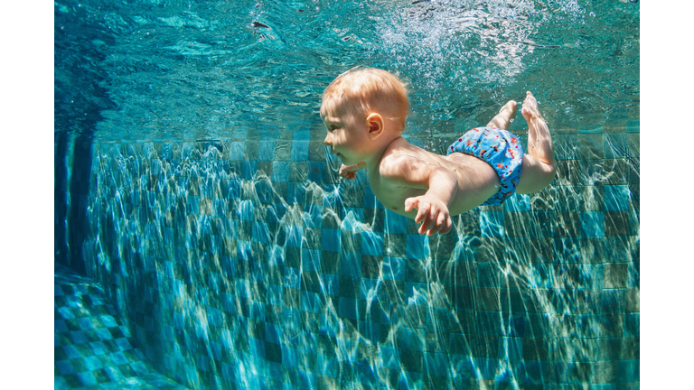 Child jump underwater into swimming pool