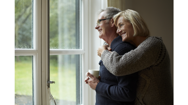 Senior woman embracing man in front of door