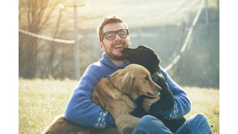 young man having a fun with dogs in the nature