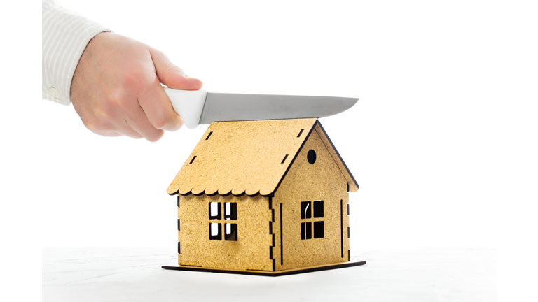 Kitchen knife in hand cutting a house model in half