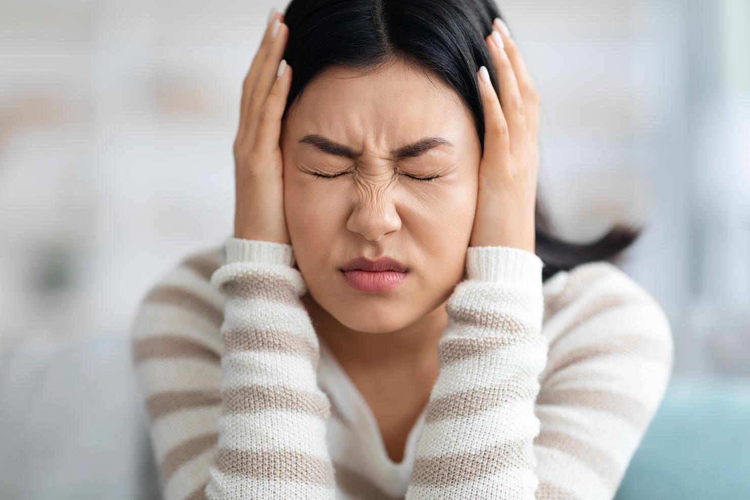 Emotional Asian Woman Covering Ears With Hands At Home