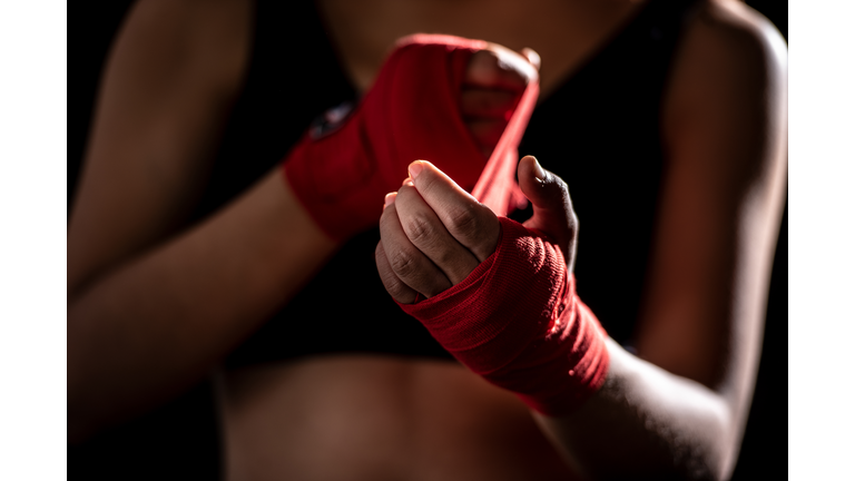Health care women are exercising by punching and are wrapped in red cloth at the hands before punching in the gym.