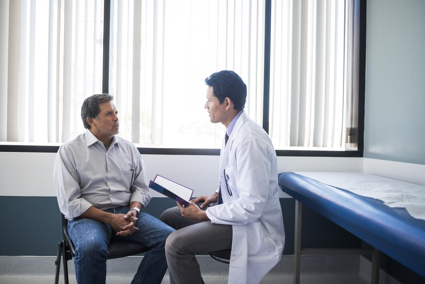 Side view of doctor talking with senior patient in hospital