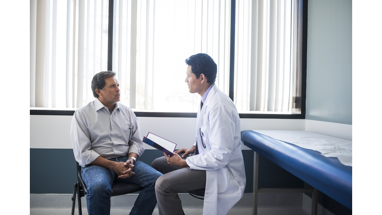 Side view of doctor talking with senior patient in hospital