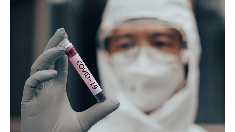 COVID-19 named by WHO for Novel coronavirus NCP concept. Doctor or lab technician in PPE suit holding blood sample with novel (new) coronavirus in Wuhan, Hubei Province, China, medical and healthcare