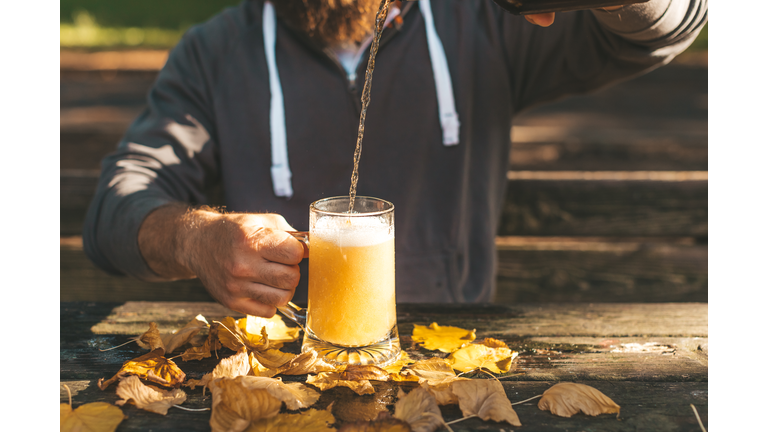 Cropped image of young man pouring fresh beer into pint glass, autumn holidays celebration and Oktoberfest concept