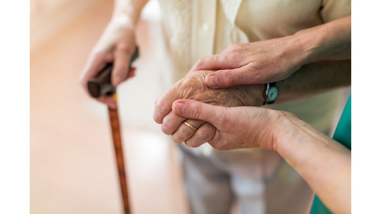 Nurse consoling her elderly patient by holding her hands