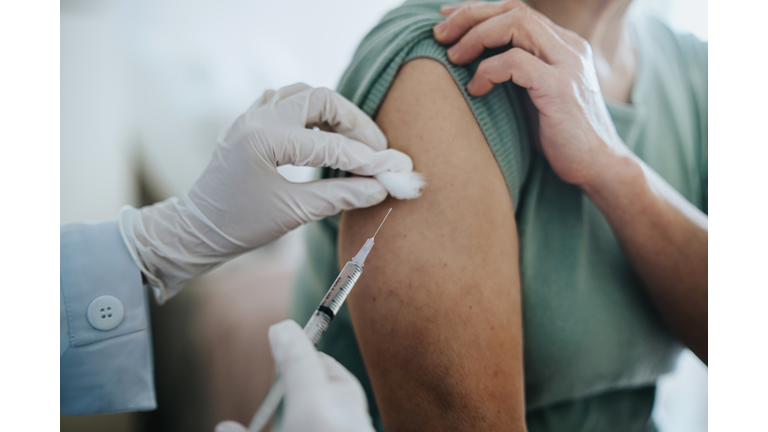 Close up of senior Asian woman getting Covid-19 vaccine in arm for Coronavirus immunization by a doctor at hospital. Elderly healthcare and illness prevention concept