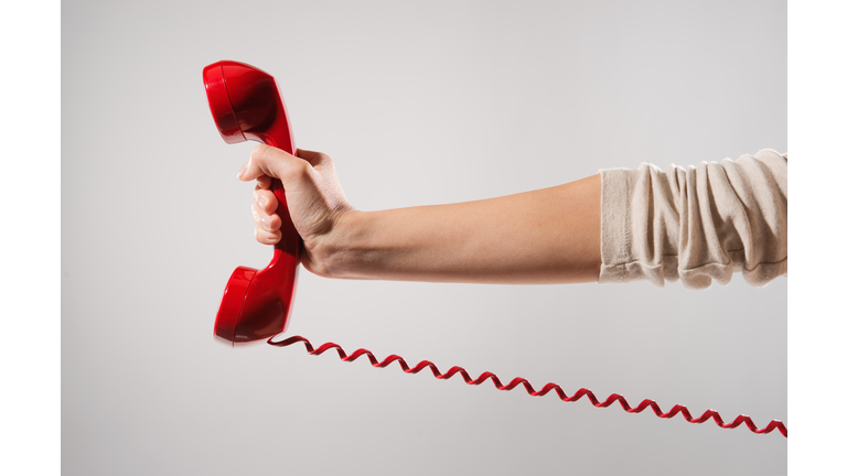 Woman's hand holding red phone