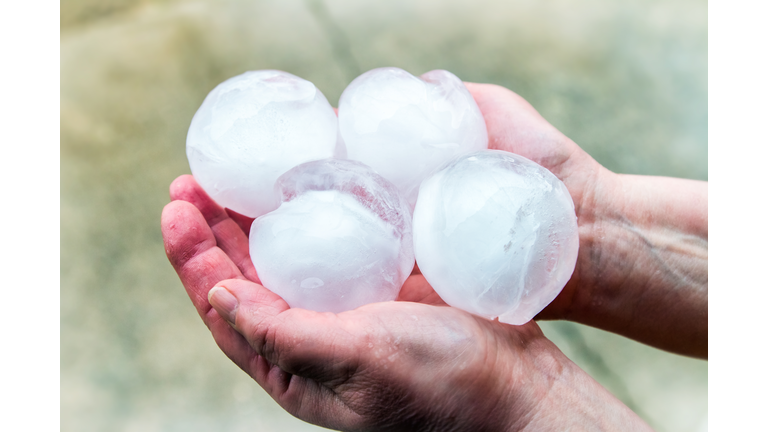 Unrecognizable women holding and showing group of very big ice hailstones in her hands in the end of winter season in march outdoor