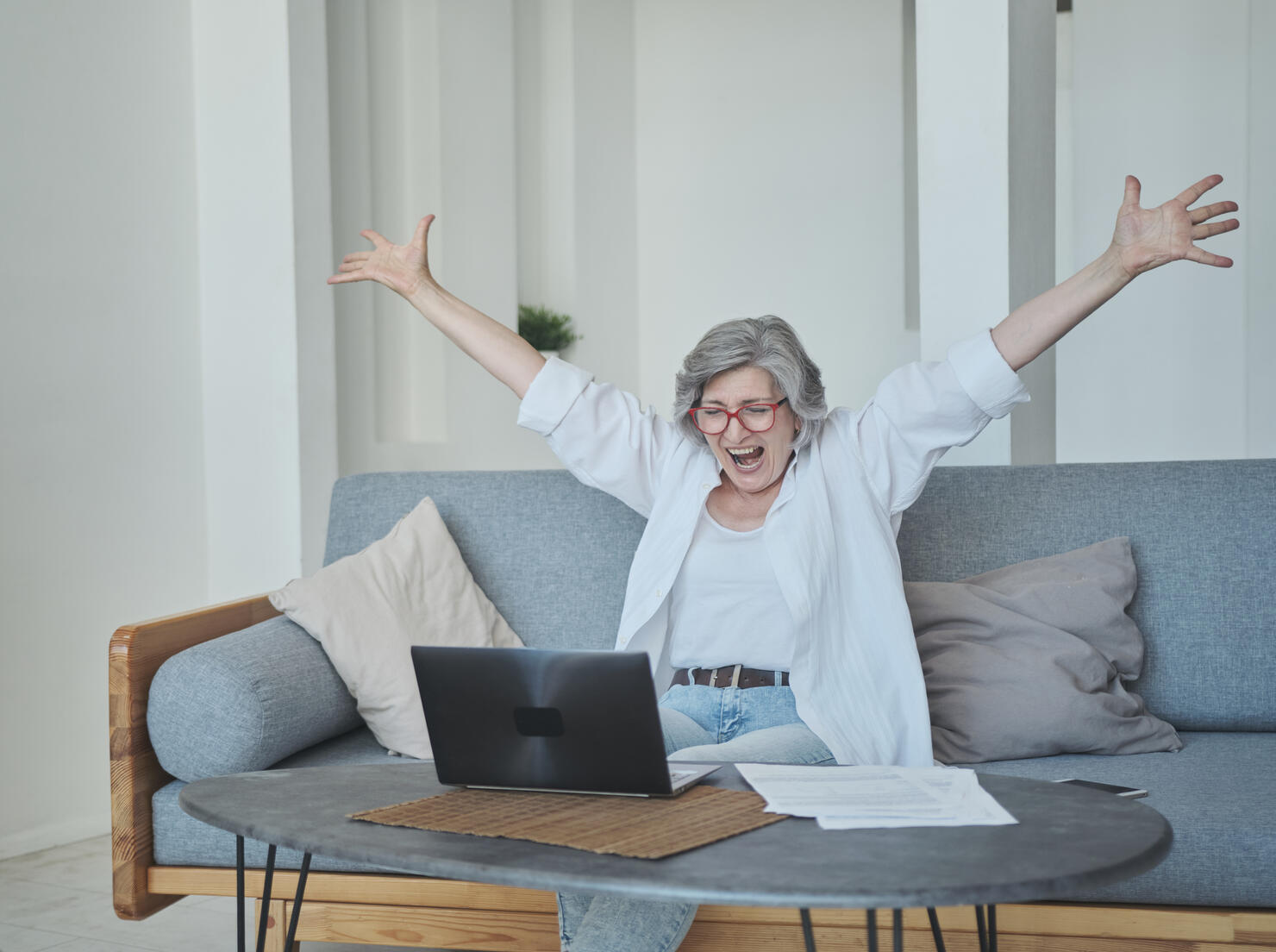 An excited senior woman is actively rejoicing and expressing her emotions about winning the online lottery