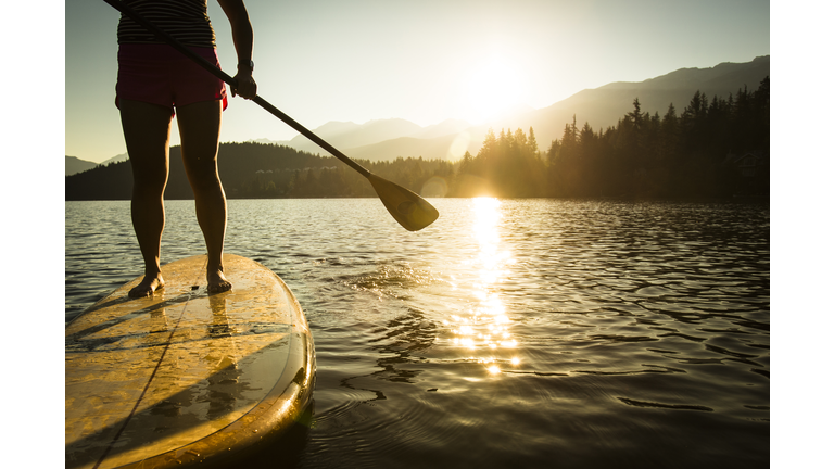 Paddleboarding on lake during sunrise or sunset.
