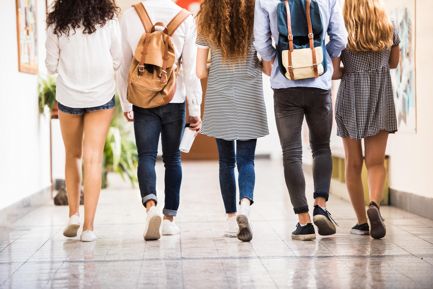 Unrecognizable teenage students in high school hall.