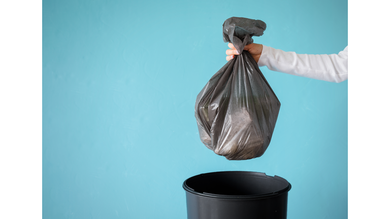 Hand holding garbage in plastic bag
