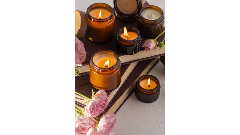 A set of different aroma candles in brown glass jars. Scented handmade candle. Soy candles are burning in a jar. Aromatherapy and relax in spa and home. Still life. Fire in brown jar