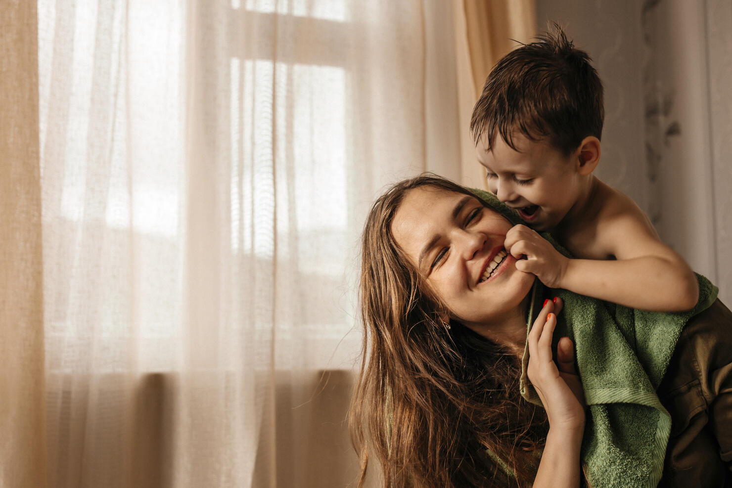 Happy mother with playful little son at home