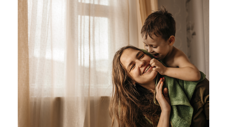 Happy mother with playful little son at home