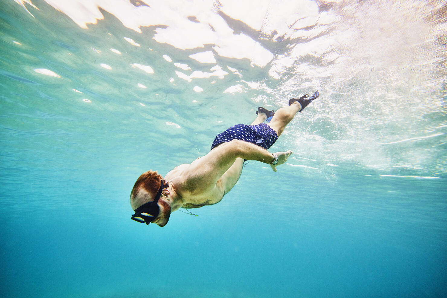 Wide shot underwater view of man snorkeling in tropical sea