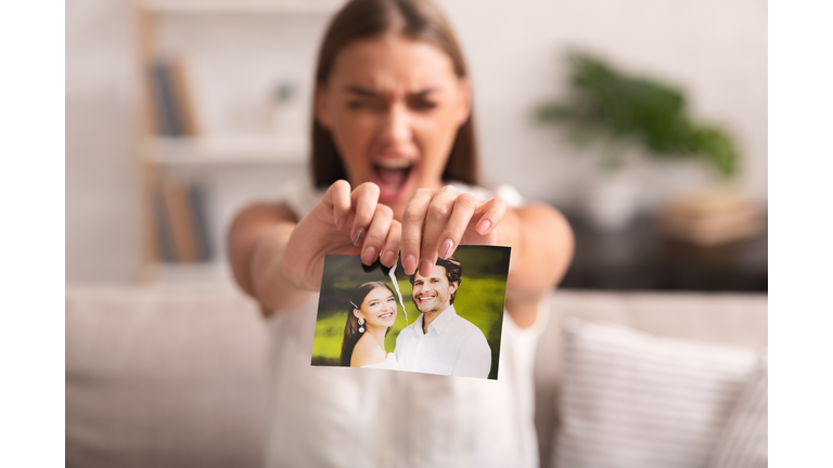 Furious Woman Ripping Wedding Photo Sitting On Sofa Indoor