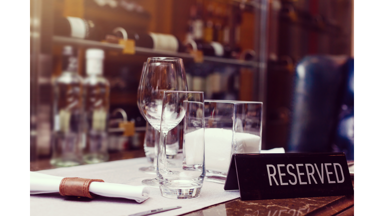 Reserved sign on a table in restaurant. Empty glasses set in restaurant