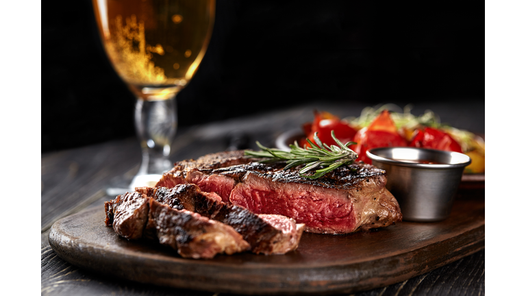 Juicy steak medium rare beef with spices on wooden board on table