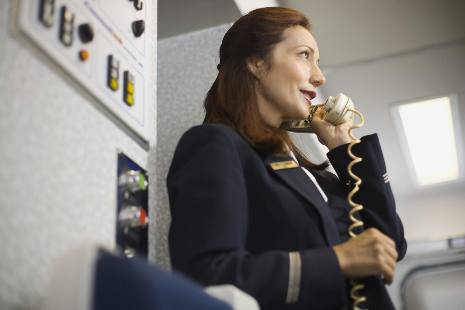 Stewardess instructing passengers on airplane over the loudspeaker