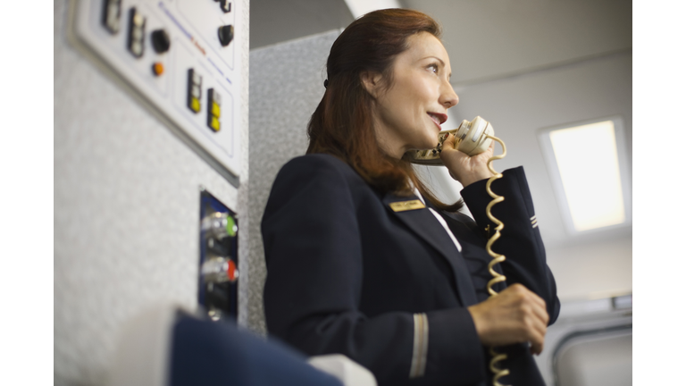 Stewardess instructing passengers on airplane over the loudspeaker