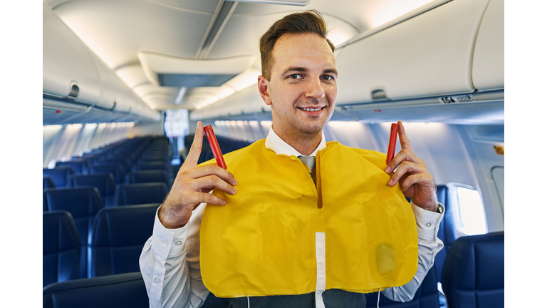 Cheerful handsome flight attendant wearing a lifejacket
