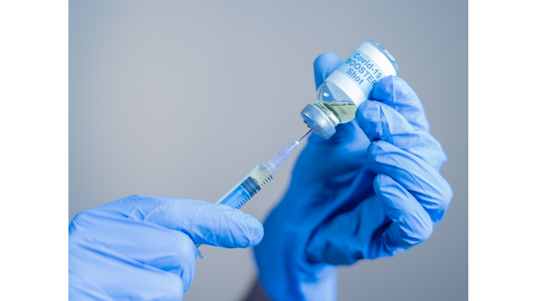 Focus on syringe, close up of doctor or nurse hands taking covid vaccination booster shot or 3rd dose from syringe